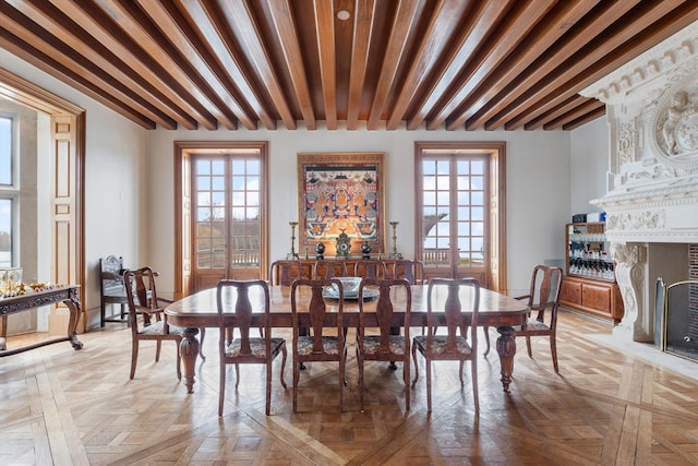 dining room with beamed ceiling, a healthy amount of sunlight, and light parquet floors