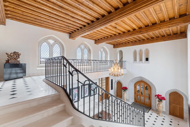 stairway with beam ceiling, an inviting chandelier, and wood ceiling