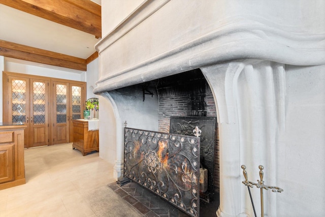 room details featuring beamed ceiling and a brick fireplace