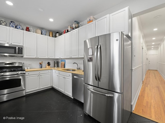 kitchen with wood counters, sink, white cabinetry, and stainless steel appliances