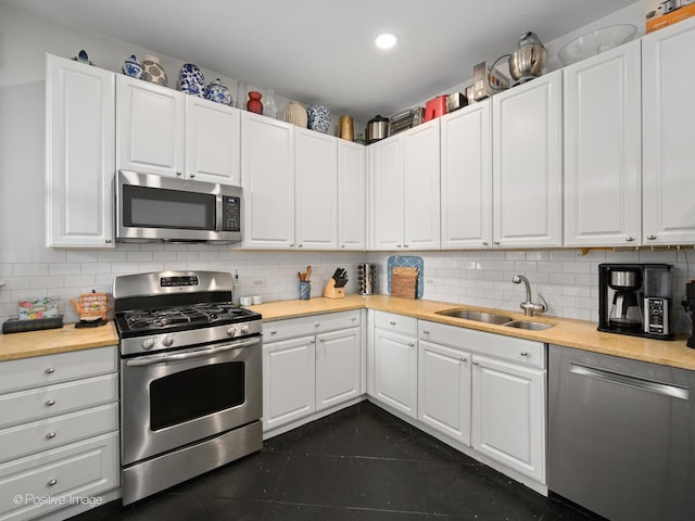 kitchen with tasteful backsplash, sink, white cabinets, and appliances with stainless steel finishes