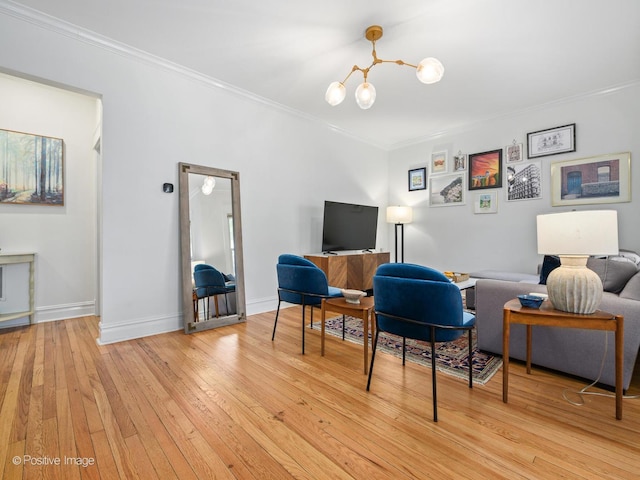 living area featuring crown molding, a chandelier, and light wood-type flooring