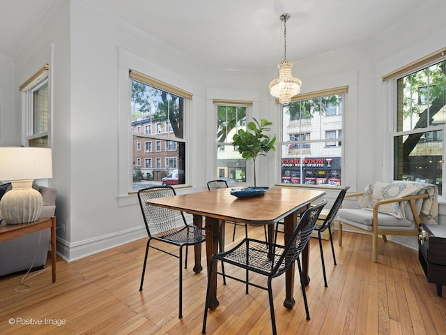 dining area featuring crown molding, light hardwood / wood-style floors, and a chandelier