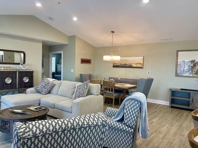 living room with lofted ceiling, a notable chandelier, and light wood-type flooring