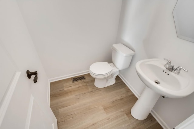 bathroom with hardwood / wood-style flooring, toilet, and sink