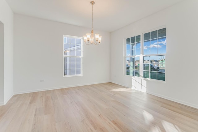 spare room with light hardwood / wood-style floors and a chandelier