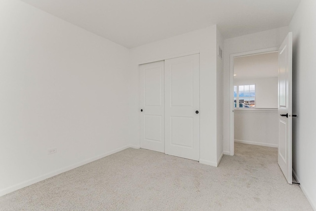 unfurnished bedroom featuring light carpet and a closet