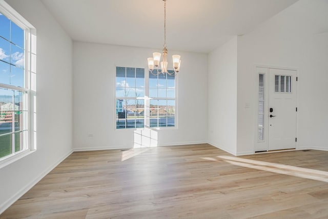 unfurnished dining area featuring a chandelier and light wood-type flooring