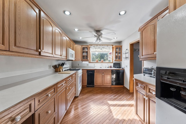 kitchen featuring ceiling fan, sink, white appliances, and light wood-type flooring