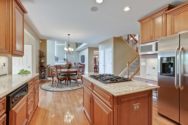 kitchen featuring light stone countertops, a center island, stainless steel appliances, an inviting chandelier, and pendant lighting