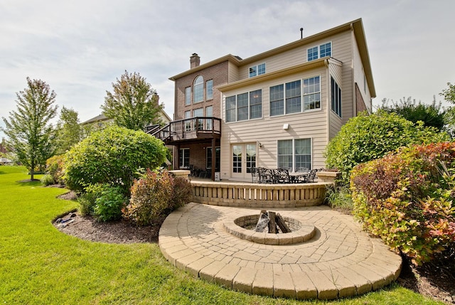 rear view of property featuring a yard, an outdoor fire pit, a patio area, and a wooden deck