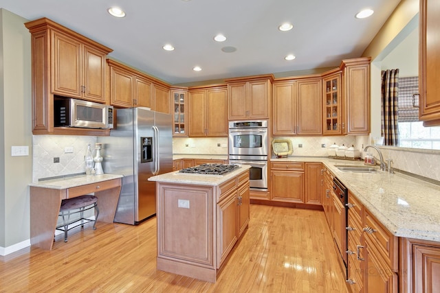 kitchen with light stone counters, stainless steel appliances, sink, light hardwood / wood-style flooring, and a kitchen island