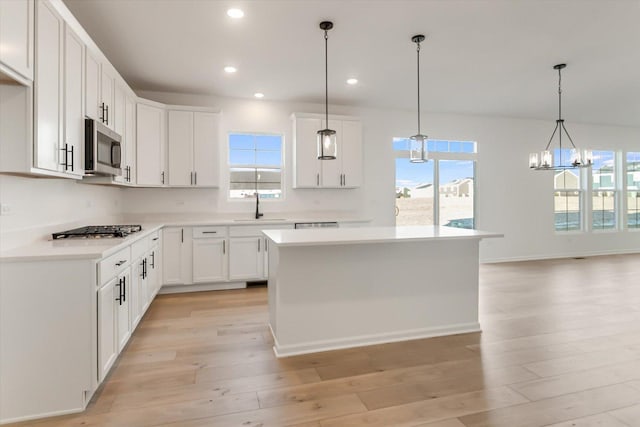 kitchen with white cabinets, hanging light fixtures, sink, appliances with stainless steel finishes, and a chandelier