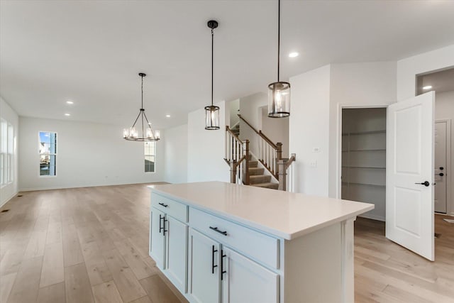 kitchen with pendant lighting, a notable chandelier, white cabinets, a center island, and light hardwood / wood-style floors