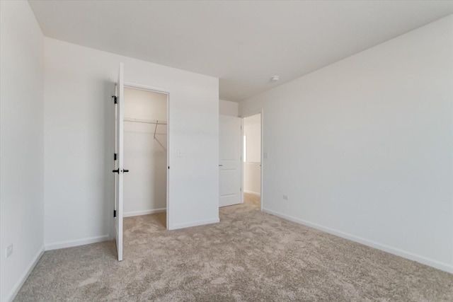 unfurnished bedroom featuring light colored carpet, a spacious closet, and a closet