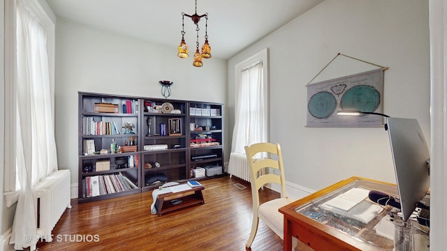 office space featuring wood-type flooring and radiator heating unit