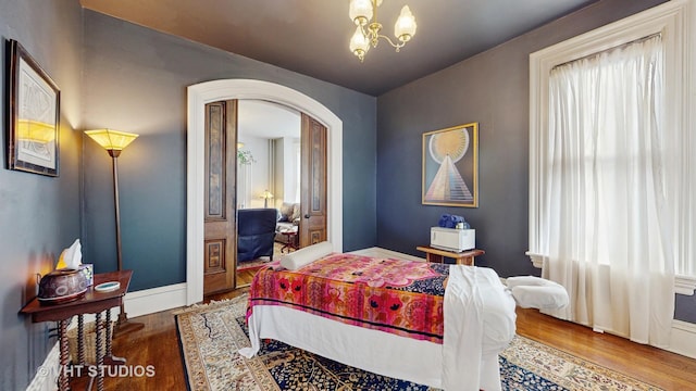 bedroom with wood-type flooring and an inviting chandelier