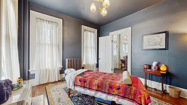 bedroom with hardwood / wood-style flooring, radiator heating unit, and a chandelier