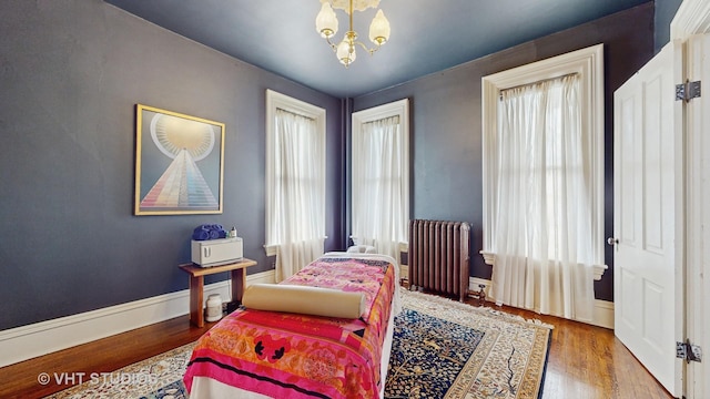 sitting room with a chandelier, radiator heating unit, and hardwood / wood-style floors