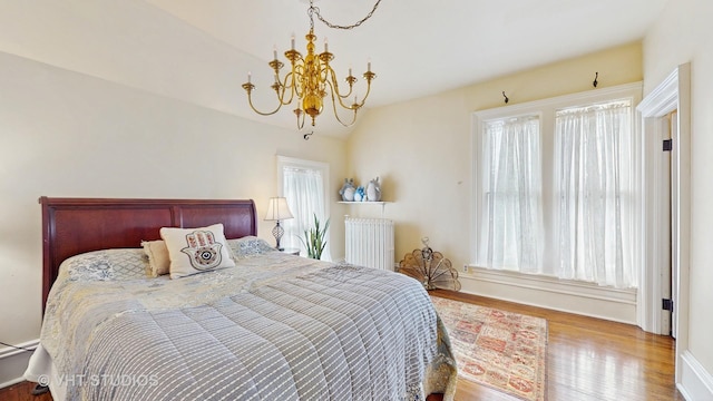 bedroom with wood-type flooring, radiator heating unit, and a chandelier