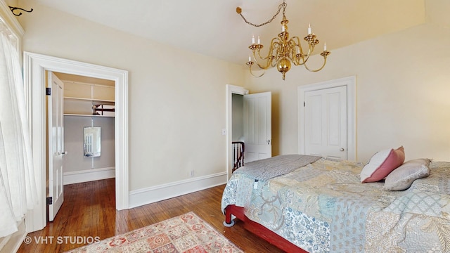 bedroom featuring a spacious closet, dark wood-type flooring, a closet, and a notable chandelier