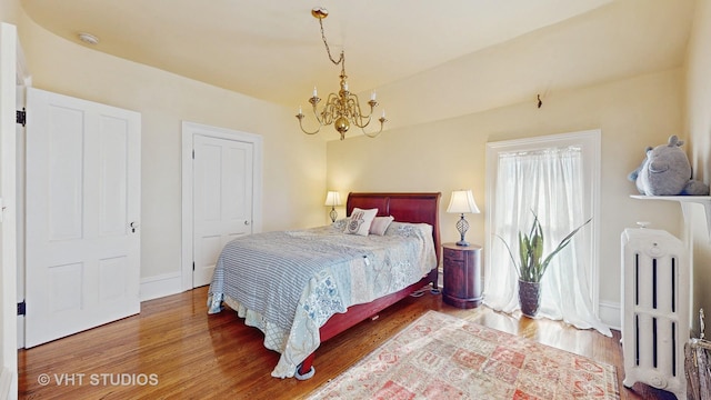 bedroom featuring radiator heating unit, hardwood / wood-style floors, and a notable chandelier