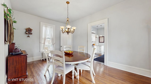 dining area with dark wood-type flooring, a chandelier, and radiator