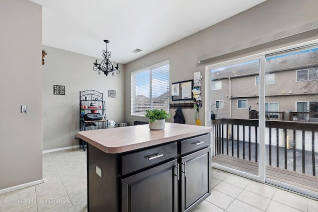 kitchen featuring pendant lighting, a center island, light tile patterned floors, and a chandelier