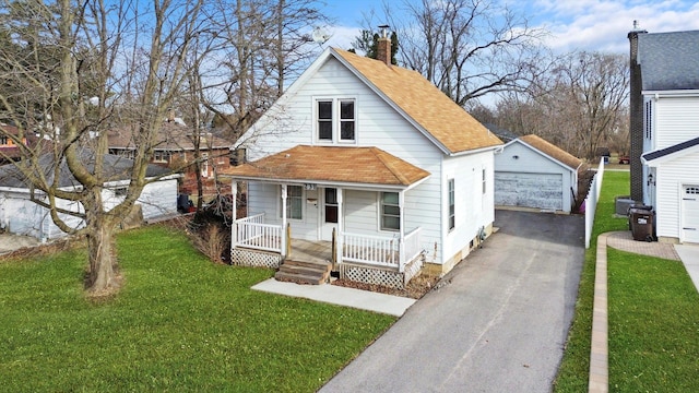 view of front of house featuring a garage, covered porch, an outbuilding, and a front lawn