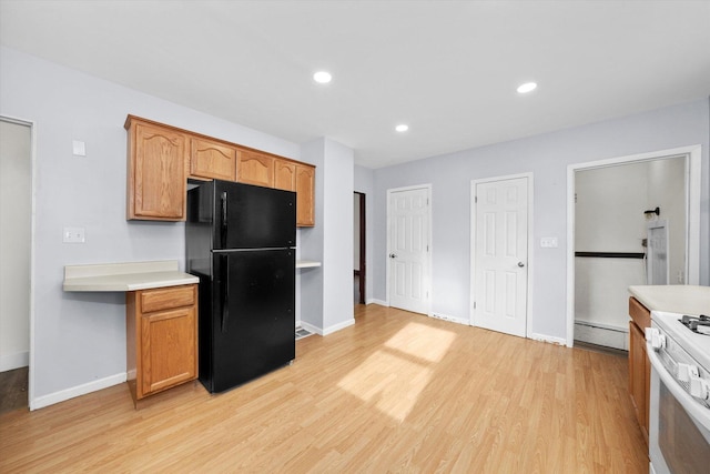 kitchen featuring black refrigerator, white stove, light hardwood / wood-style flooring, and a baseboard heating unit