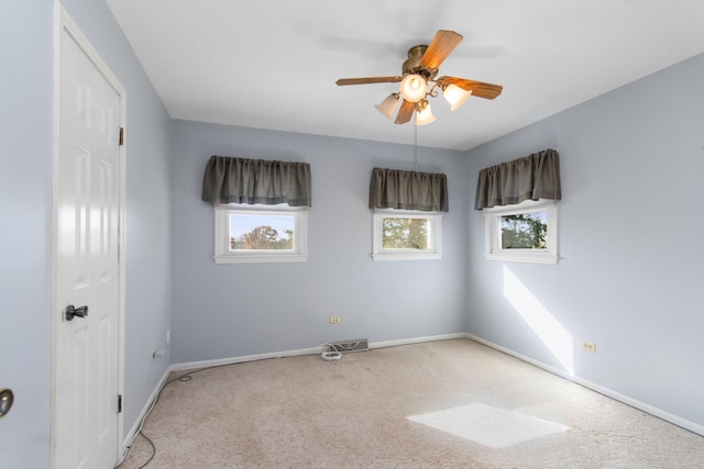 carpeted empty room with ceiling fan and plenty of natural light