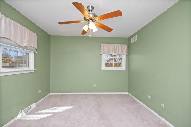 carpeted empty room with ceiling fan and a wealth of natural light