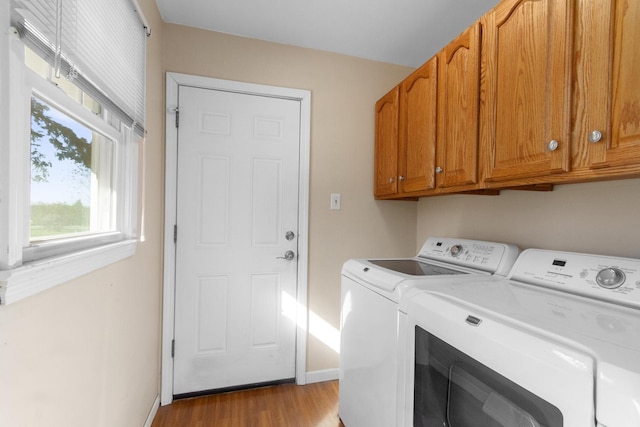 clothes washing area with washer and dryer, cabinets, and light hardwood / wood-style flooring