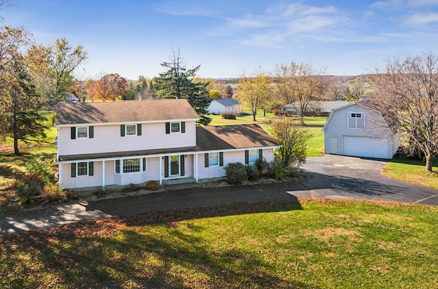 view of front of property featuring covered porch, a garage, a front lawn, and an outdoor structure