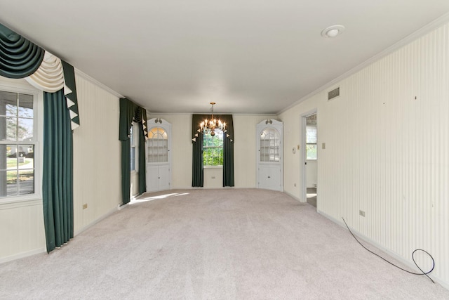 carpeted spare room featuring an inviting chandelier and crown molding