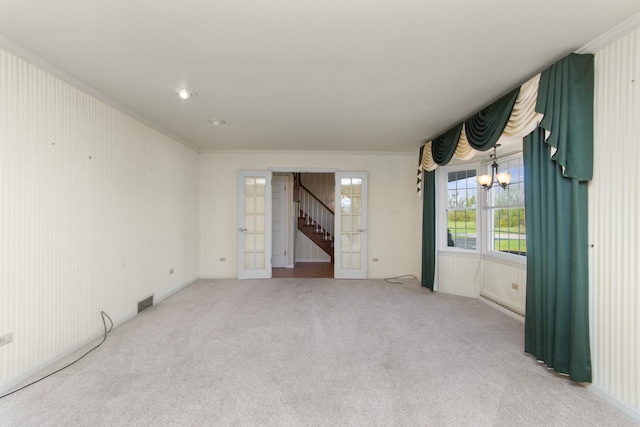 empty room featuring crown molding, french doors, carpet floors, and a notable chandelier