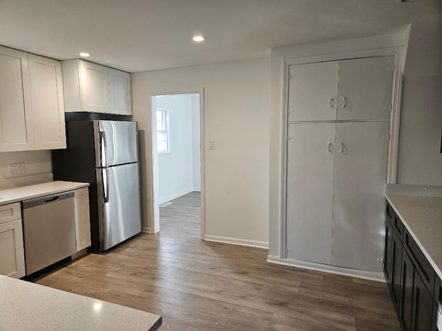 kitchen with white cabinets, light wood-type flooring, and stainless steel appliances