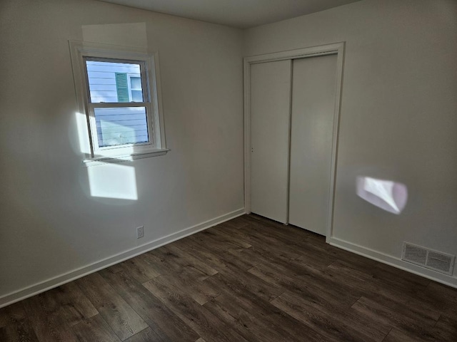 unfurnished bedroom with dark hardwood / wood-style floors and a closet