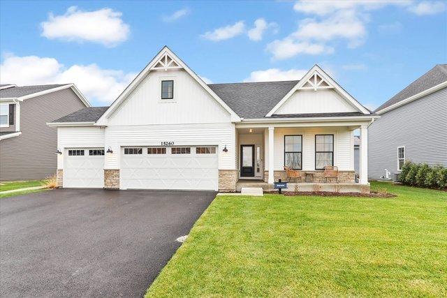 view of front of house with covered porch, a garage, and a front lawn