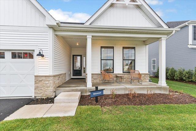 property entrance featuring a yard, covered porch, and a garage