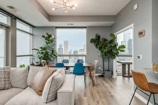 living room featuring light wood-type flooring, an inviting chandelier, a view of city, and visible vents