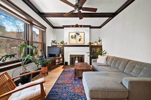 living room with a fireplace, ceiling fan, light hardwood / wood-style floors, and beam ceiling