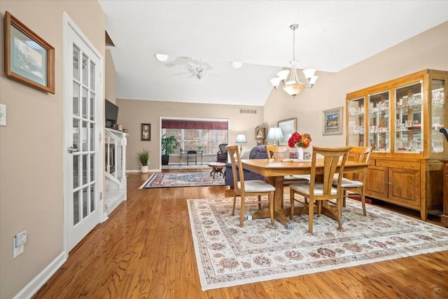 dining area featuring lofted ceiling, ceiling fan with notable chandelier, and light hardwood / wood-style flooring