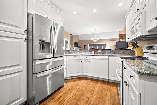 kitchen with white cabinetry, a chandelier, kitchen peninsula, and white appliances