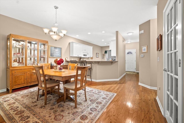 dining space with light wood-type flooring and an inviting chandelier