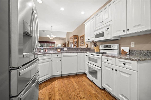 kitchen with an inviting chandelier, white cabinetry, kitchen peninsula, decorative light fixtures, and white appliances