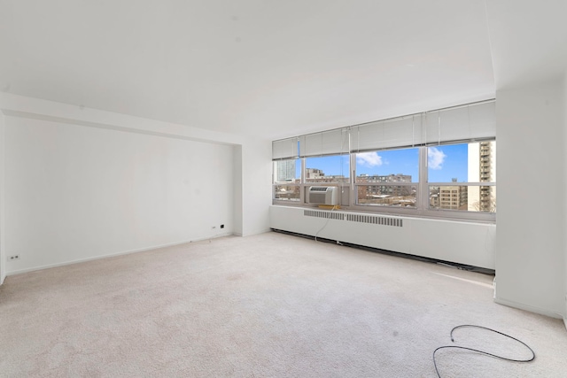 unfurnished room with radiator and light carpet