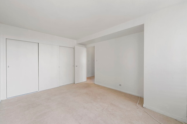 unfurnished bedroom featuring a closet and light colored carpet