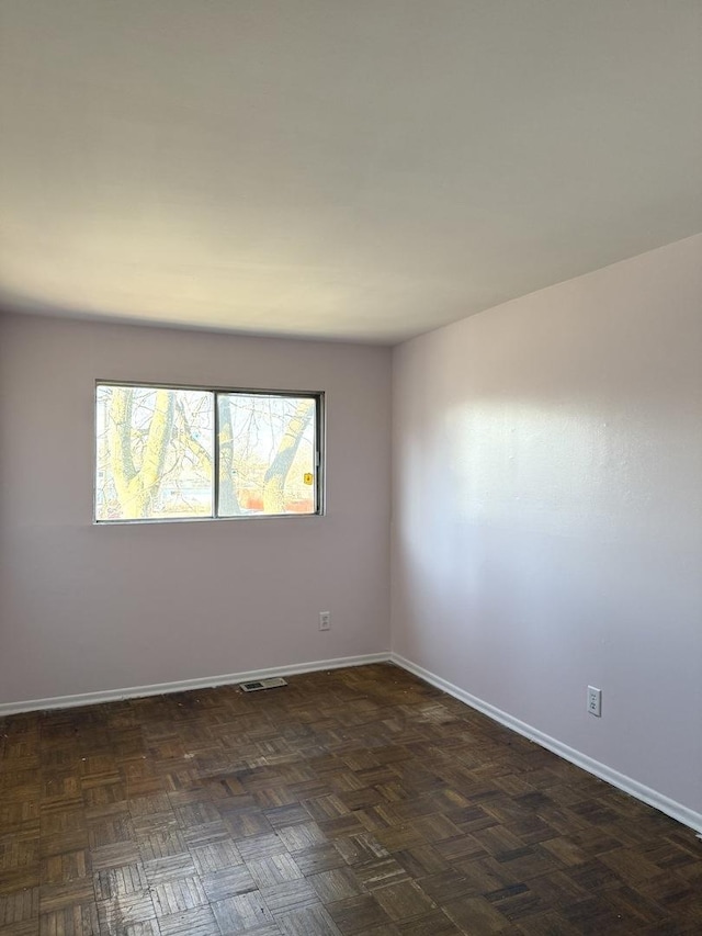 spare room featuring dark parquet floors