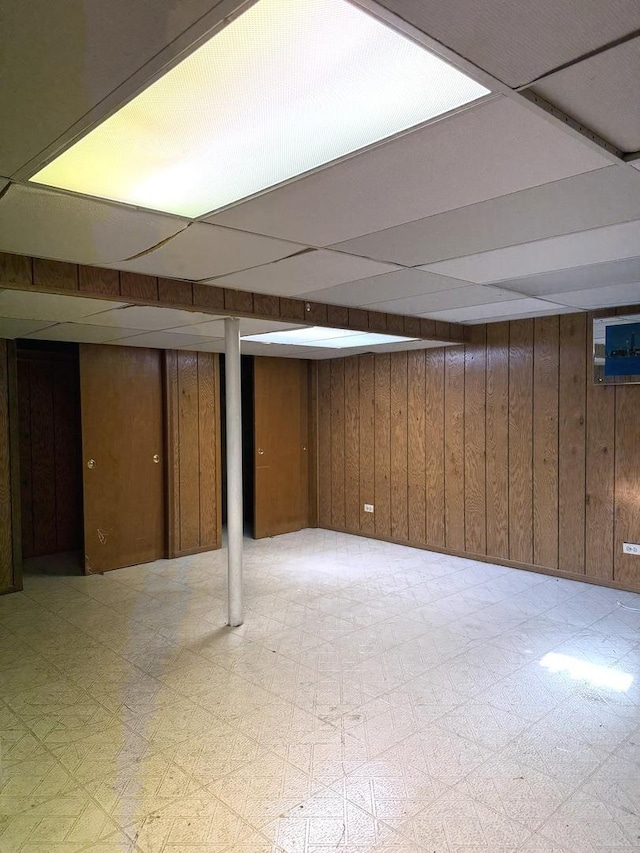 basement with wood walls and a drop ceiling